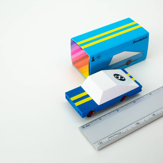 Colorful packaging box with a small car model and a ruler for scale on a white background
