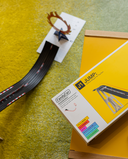 Model train track set with a box labeled 'Jump' on a yellow surface.